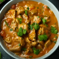 Indisches Poulet-Curry in cremiger Sauce, serviert in weisser Schale – India4U Bern