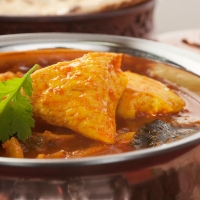 Spicy Chicken Madras in silberner Servierschale mit Curryblättern – India4U Bern