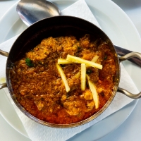 Lamm-Karahi mit Ingwerstreifen serviert in traditioneller Pfanne – India4U Bern